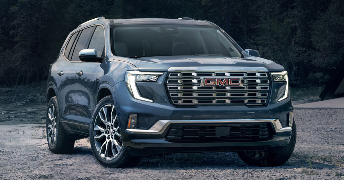 2025 GMC Acadia SUV in blue parked outdoors, showcasing bold front grille and premium design, available at Speck Buick GMC of Tri-Cities in Kennewick, WA.