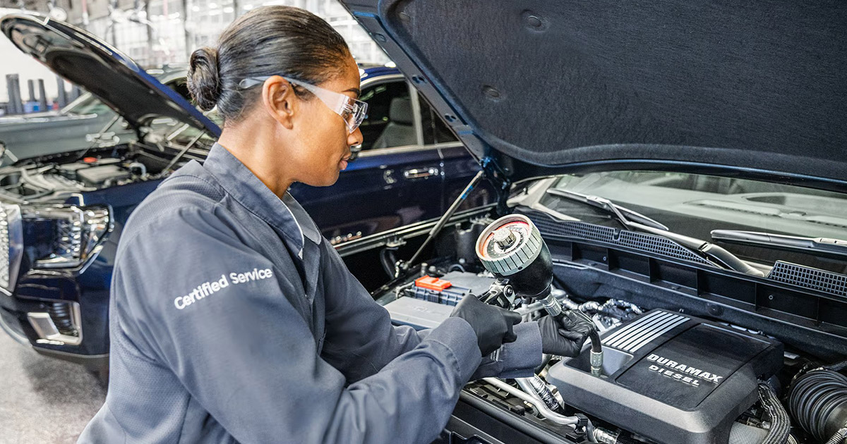 Certified GMC technician performing engine maintenance on a Duramax diesel vehicle at Speck Buick GMC of Tri-Cities service center in Kennewick, WA.